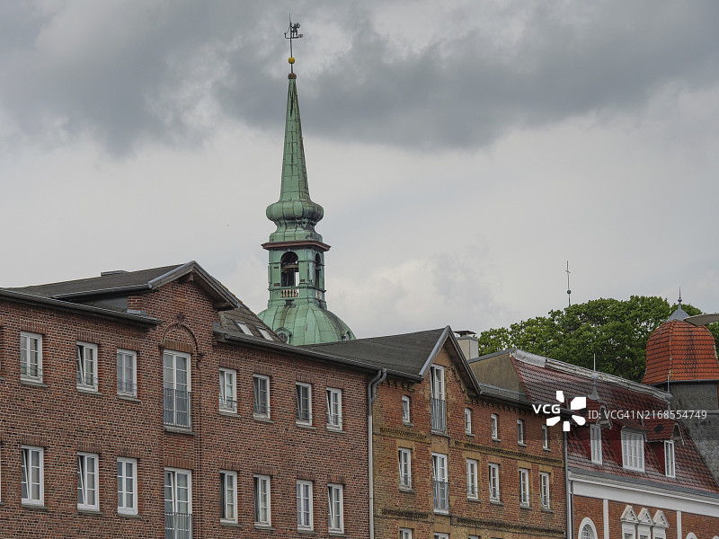 德国石勒苏益格-荷尔斯泰因州卡佩尔恩，多云天空下的历史建筑和著名教堂塔楼图片素材