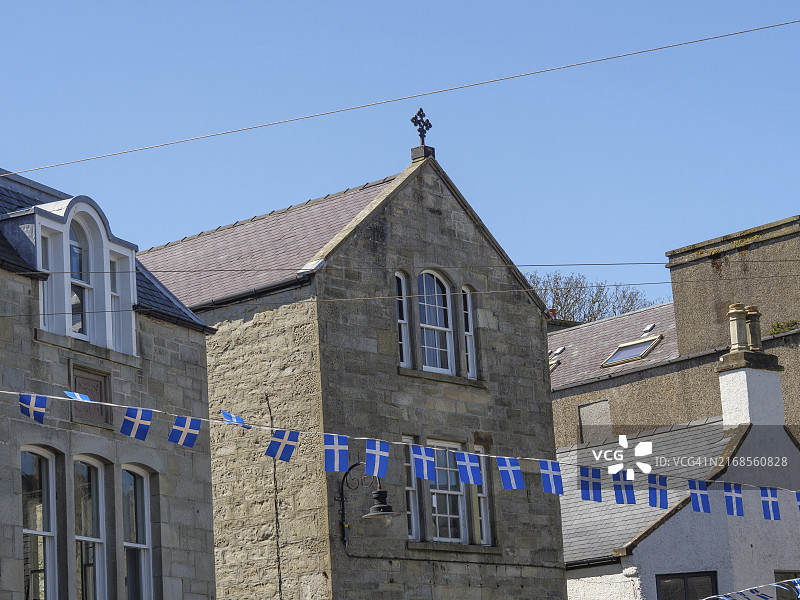 蓝色和白色三角旗装饰着历史悠久的石头建筑小镇，位于英国设得兰群岛勒威克图片素材