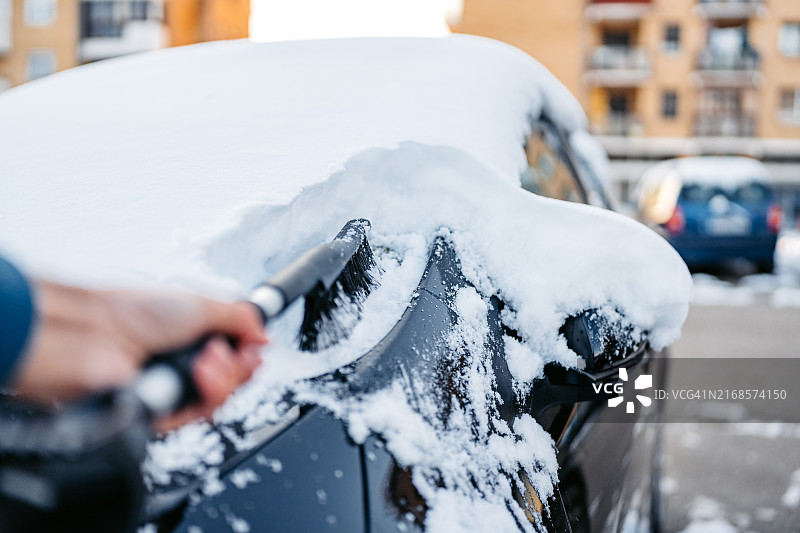 老年男人在停车场清理汽车上的积雪图片素材