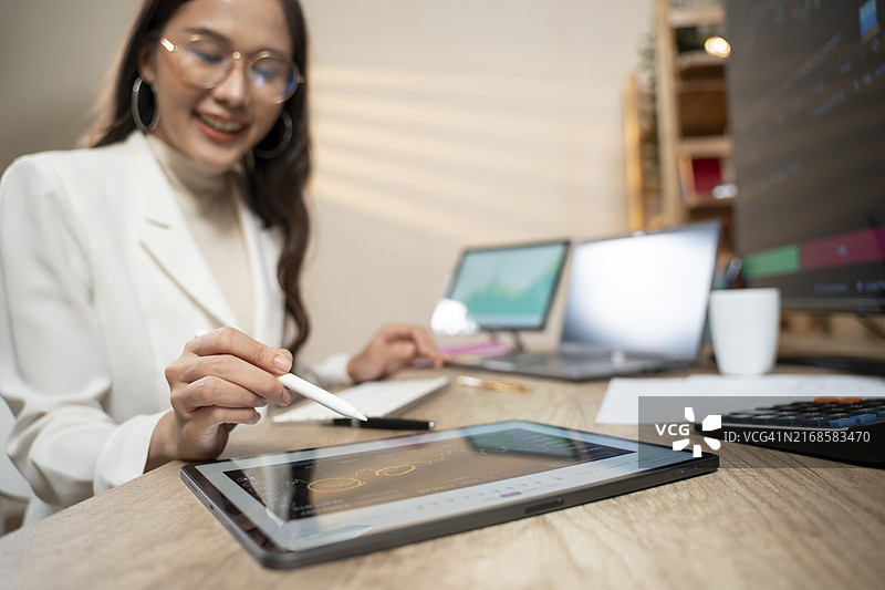 女人在电脑和平板上分析股市和交易加密货币图片素材