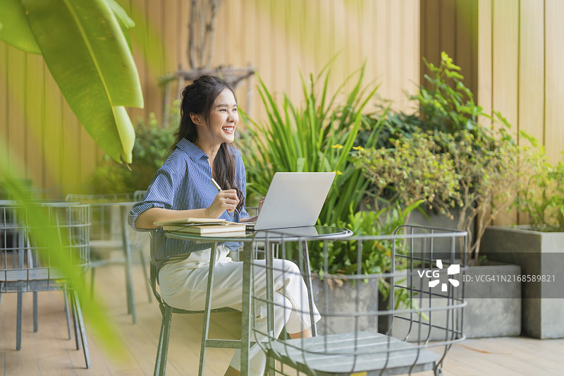 使用笔记本电脑在花园里放松的亚洲女商人图片素材