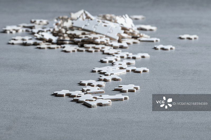 灰色表面上散落的拼图碎片，构成抽象且引人深思的画面图片素材