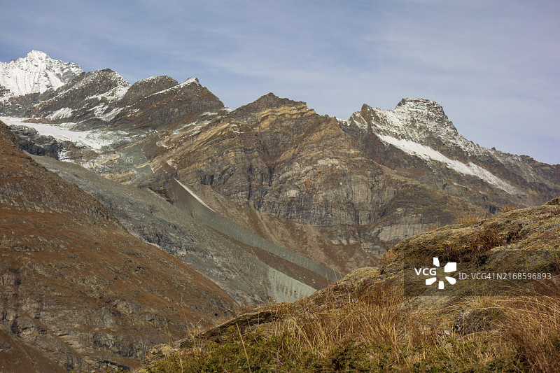 瑞士萨斯费，蓝天下冰川和雪山覆盖的贫瘠山地景观图片素材