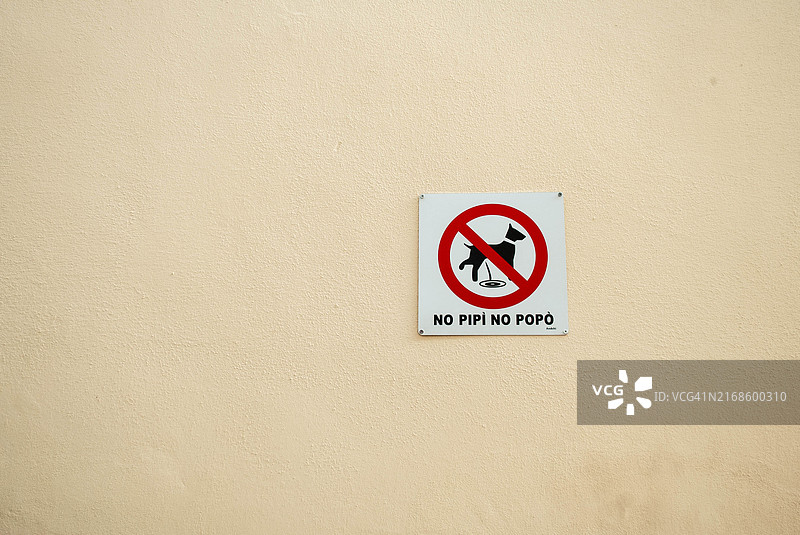 禁止狗狗在米色墙壁上小便和大便的标志图片素材