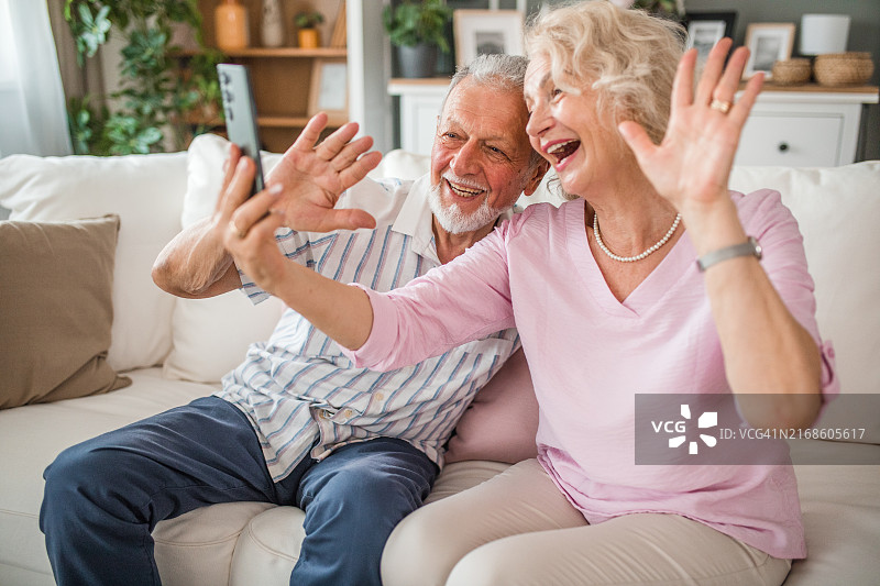 老年夫妇坐在客厅里与人进行视频通话图片素材