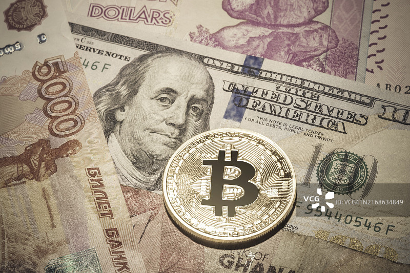 多币种纸币上的一个比特币特写图片素材