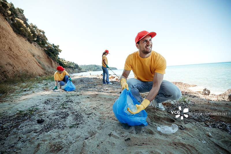 年轻男人和朋友一起清洁海滩图片素材