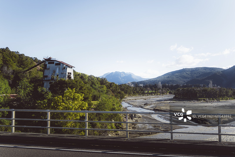 新西兰吉斯伯恩，河流和山脉景观旁的废弃房屋图片素材