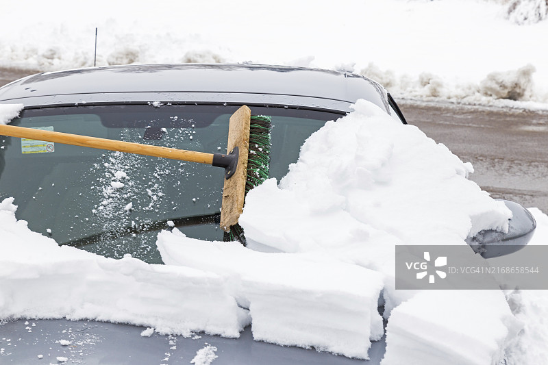 用扫帚清扫积雪覆盖的汽车图片素材
