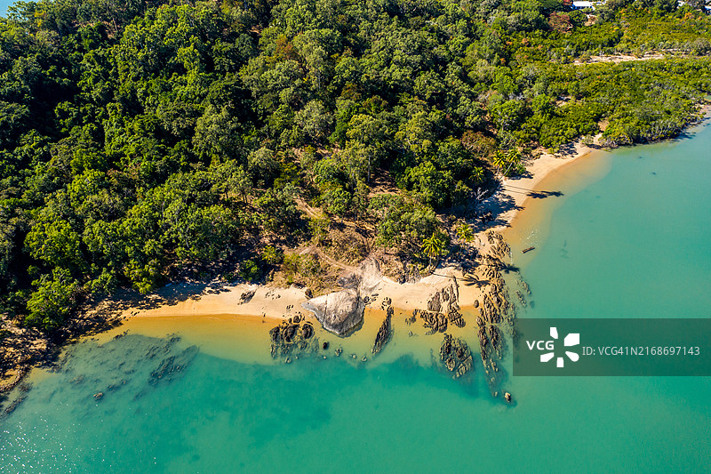 阳光明媚的午后，三位一体海滩展现出清澈的碧绿海水和茂盛的绿色海岸线图片素材