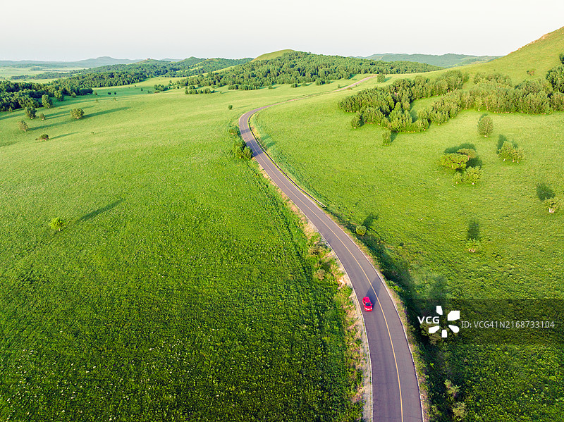 汽车行驶在夏季草原的道路上图片素材