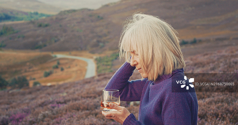 身穿苏格兰高地传统裙子的女子品尝单一麦芽威士忌图片素材