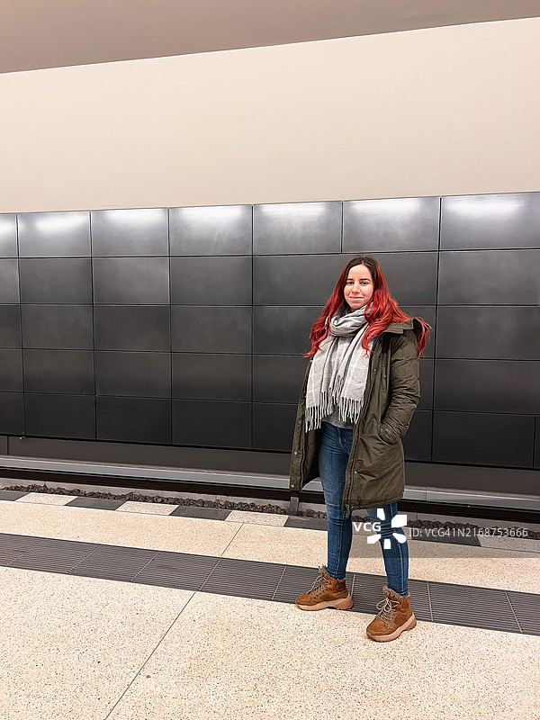 年轻女子站在地铁站台上靠墙微笑图片素材