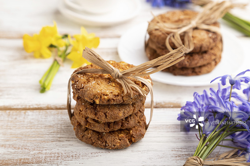 白色木质背景上的燕麦饼干、雪滴花、风铃草、水仙花和咖啡图片素材