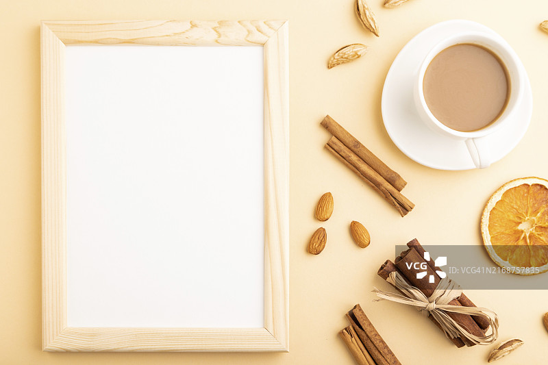 橙色背景上的木制相框、杏仁、肉桂和咖啡杯样机图片素材