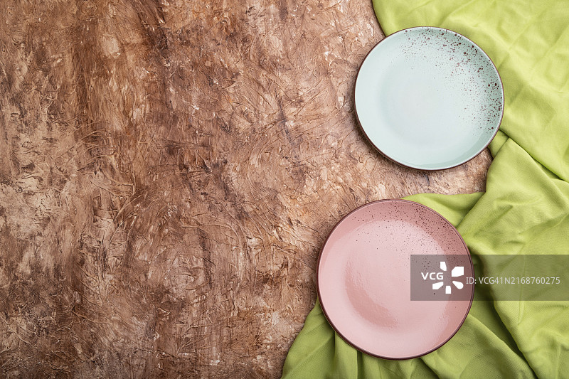棕色水泥背景上的蓝色和粉色空盘子图片素材