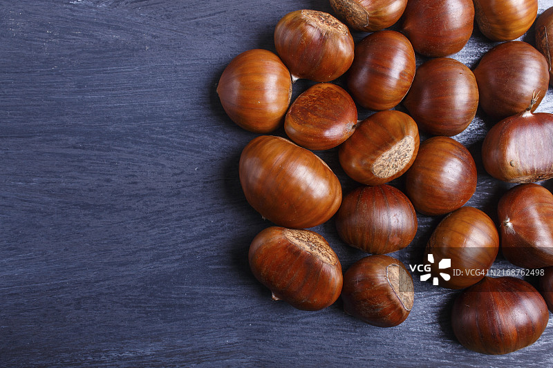 黑色木质背景上带复制空间的甜栗子堆，顶视图图片素材