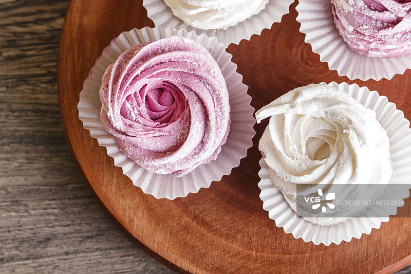 灰色木质背景圆形木板上的粉白色棉花糖（选择性焦点）图片素材