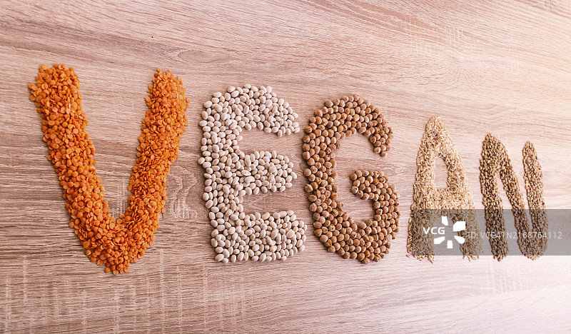用扁豆、荞麦、豆类、大米和鹰嘴豆在木制背景上制成的“素食主义者”字样图片素材