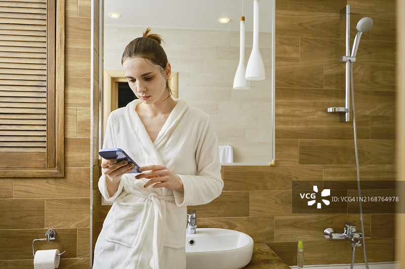 年轻女子敷面膜上网消磨时间图片素材