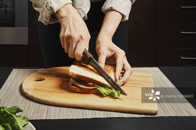 正在切自制俱乐部三明治的女士图片素材