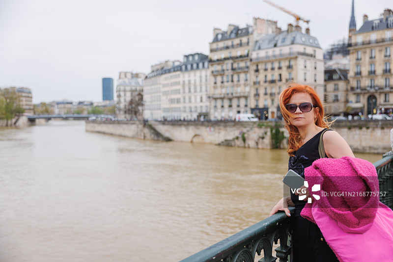 站在塞纳河栅栏旁的美丽中年妇女图片素材