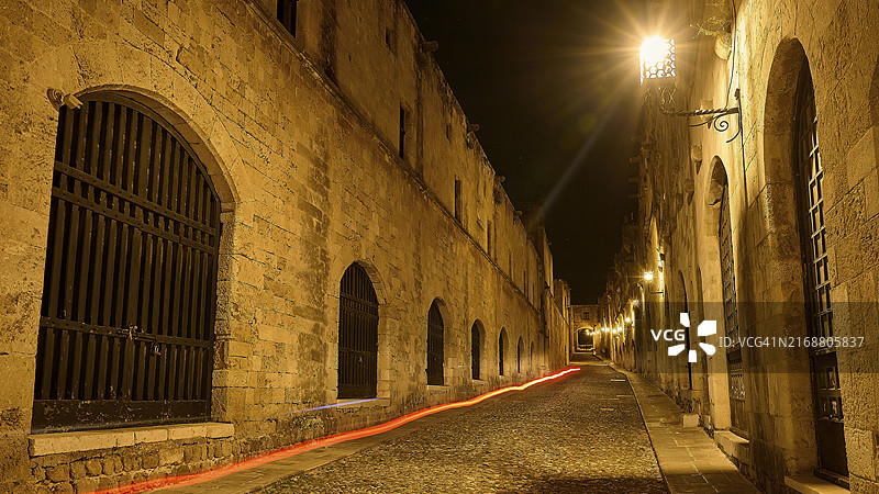 罗德岛古城宁静夜晚石街，温暖灯光与光轨图片素材