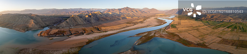 吉尔吉斯斯坦托克托古尔水库日落时分，纳伦河穿越群山和田野全景（航拍）图片素材