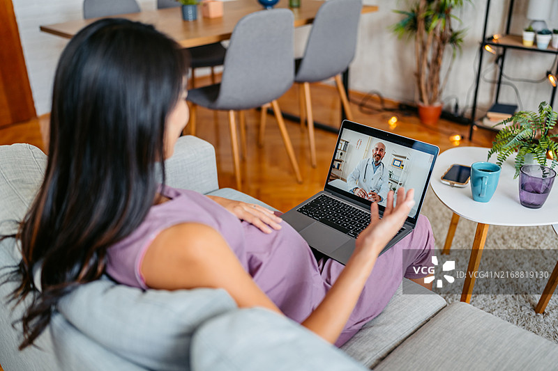 中年怀孕亚洲女性通过笔记本电脑在线咨询医生关于怀孕事宜图片素材