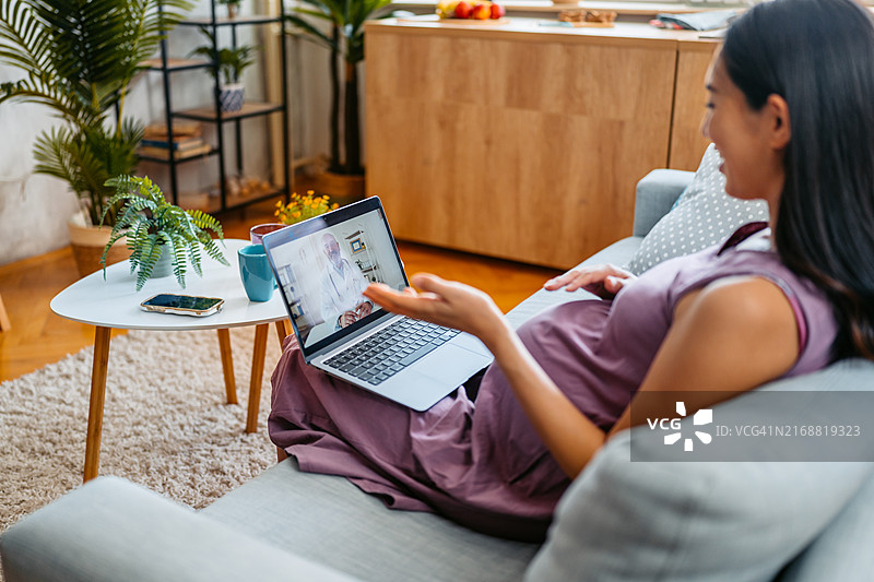 中年怀孕亚洲女性通过笔记本电脑在线咨询医生关于怀孕事宜图片素材
