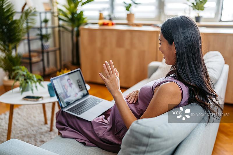 中年怀孕亚洲女性通过笔记本电脑在线咨询医生关于怀孕事宜图片素材
