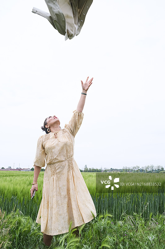 女子在意大利帕维亚省的麦田里抛撒麦子图片素材