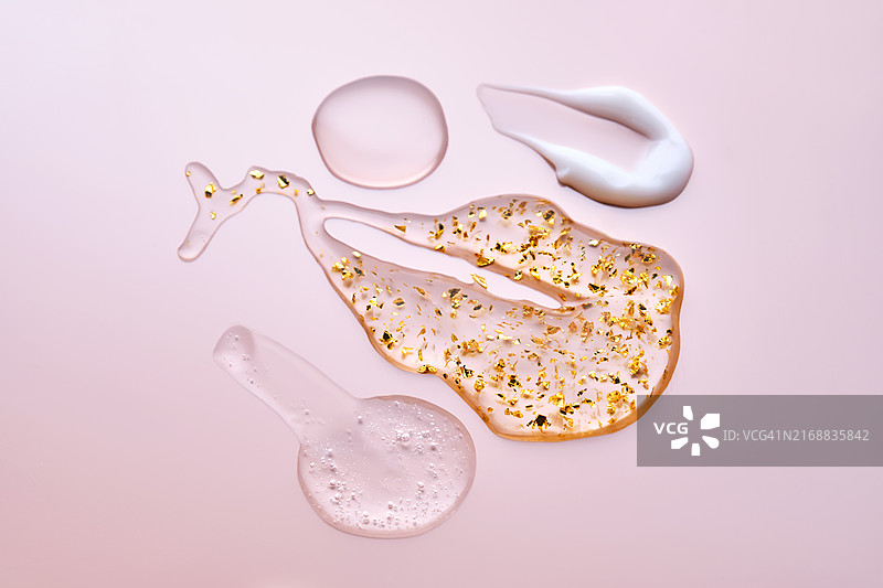 粉色背景上的面部精华、霜、油和含24K金精华液纹理图片素材