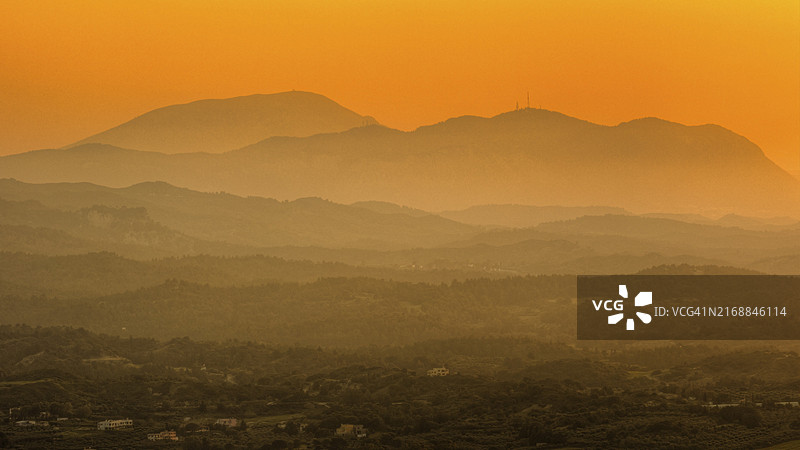 从费莱里莫斯山向西南方向望去，黄昏时分橙色光芒的山脉，背景是雾蒙蒙的景色，费莱里莫斯，希腊罗德岛伊亚利索斯古国附近的丘陵图片素材