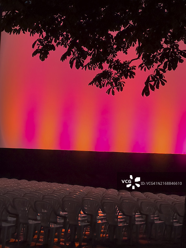 露天电影院的空座位，明亮的舞台在红色和橙色光芒下图片素材