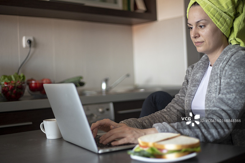 自由职业者在家工作，穿着睡袍用笔记本电脑打字，喝咖啡，享受家庭氛围，浏览网页，阅读护肤建议图片素材