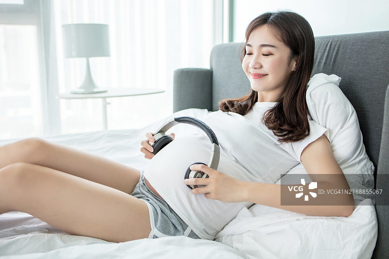 孕妇戴着耳机在肚子上听音乐图片素材