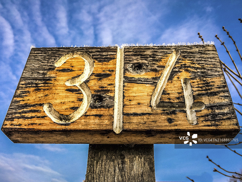 蓝色天空下，略带风化的木制标牌上的数字3和4图片素材