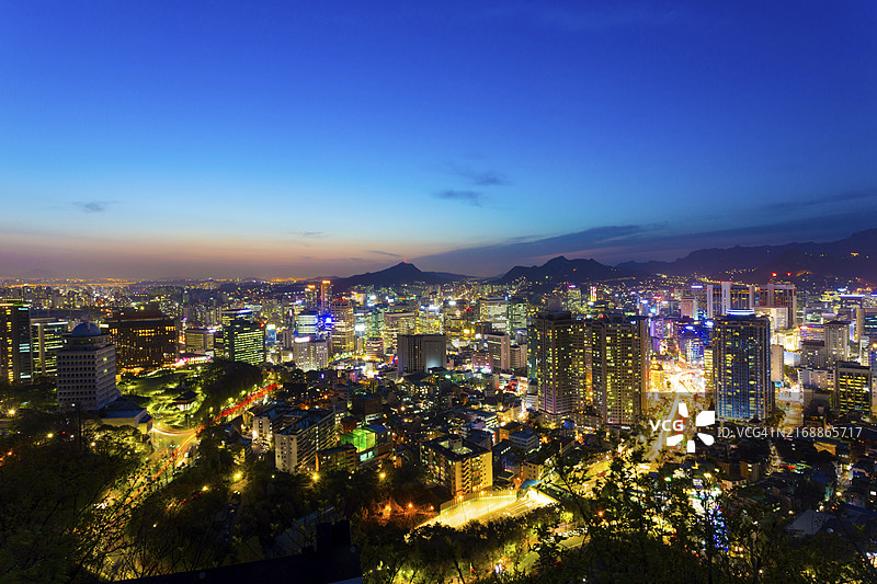 韩国首尔市中心商业建筑和山脉天际线的绚丽日落图片素材