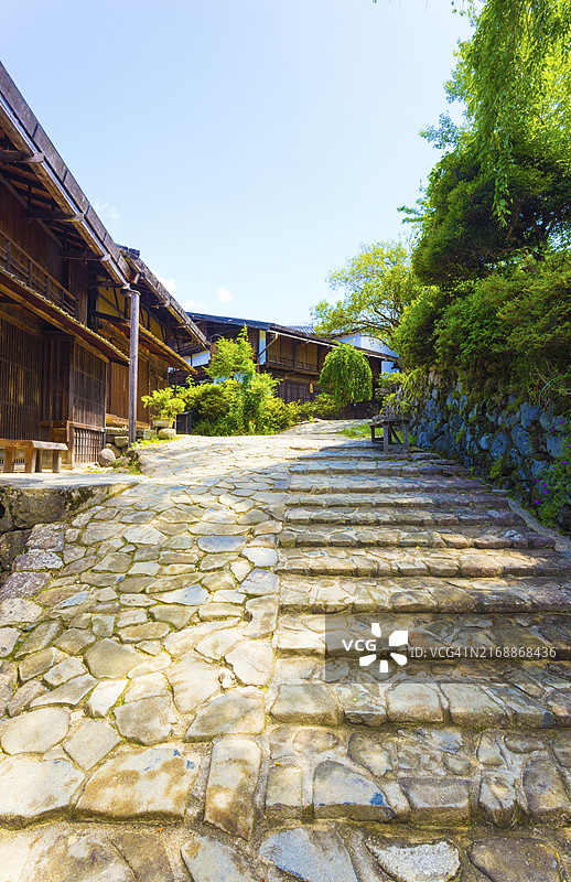 在日本历史悠久的中仙道路线的妻笼村，日式传统木屋旁的镶嵌石路。竖版图片素材