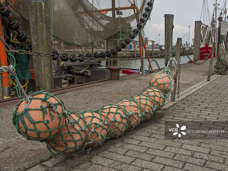 德国诺伊哈林格西尔港口边缘渔网中的大型橙色海上木筏图片素材