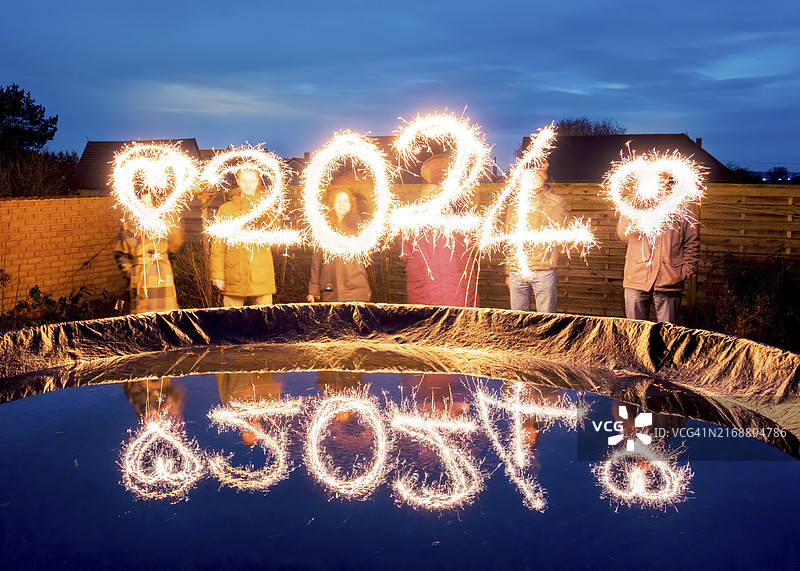 人们手持烟花棒，用火花绘制2024，新年创意图片素材