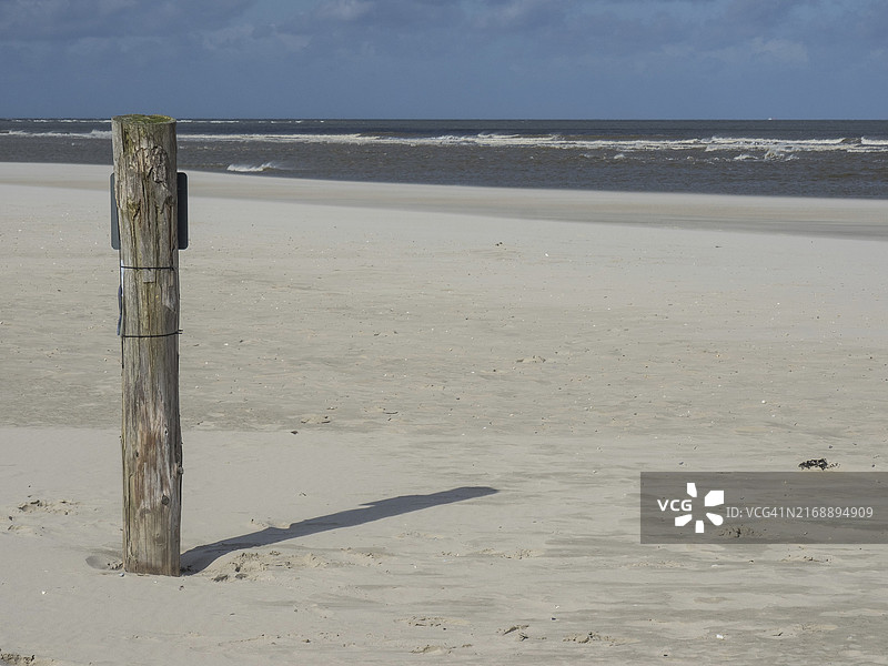 蓝天下沙滩上的木柱：德国斯皮克罗格岛海景图片素材