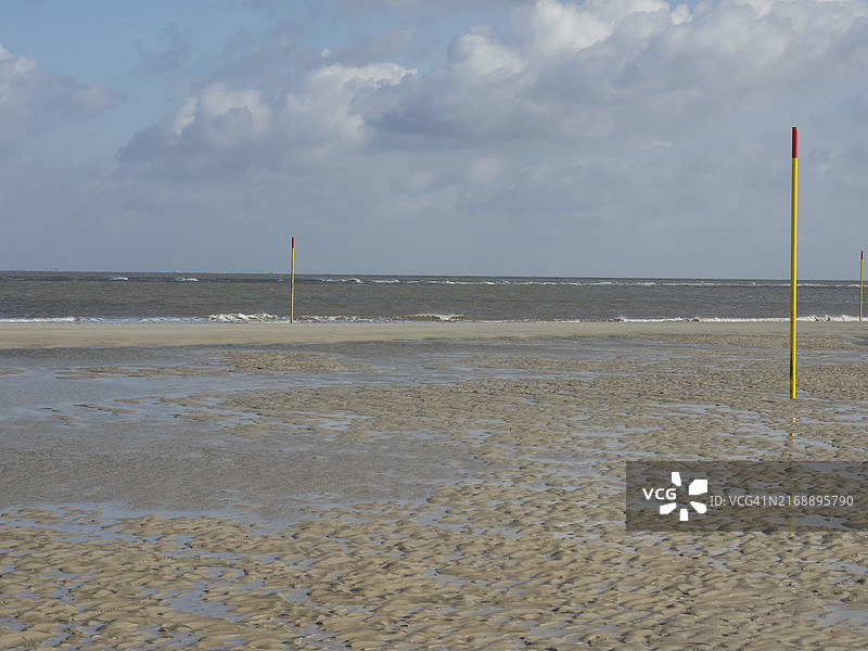 斯皮克罗格退潮海滩：可见淤泥、黄色柱子和多云天空（德国北海）图片素材