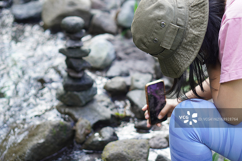 年轻女人在鹅卵石河边堆叠平衡石图片素材