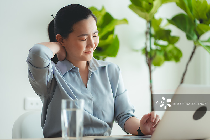 患有办公室综合症坐在家里的亚洲女人图片素材
