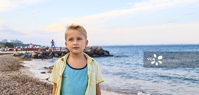 海滩上心情不好的金发男孩特写图片素材