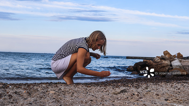 在海边沙滩上捡贝壳的少女图片素材