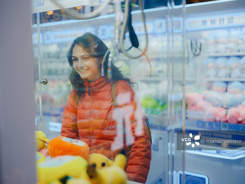 快乐的女人在玩抓娃娃机图片素材