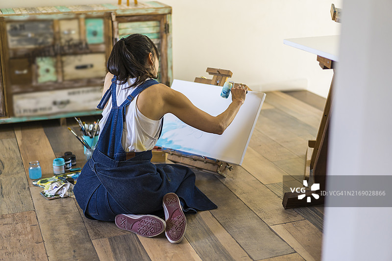 女艺术家在画布上创作蓝色抽象画图片素材